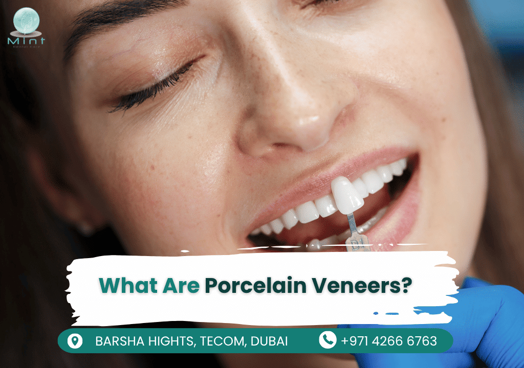 Dentist bonding thin porcelain veneer to patient's prepared tooth surface during cosmetic smile makeover procedure.